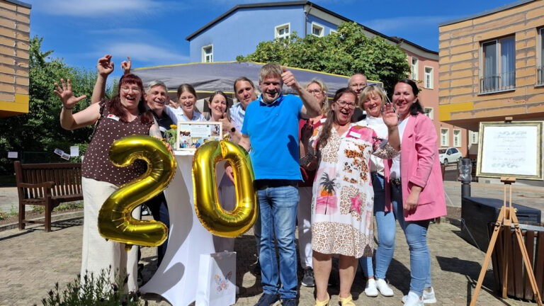 Das Bild zeigt das Team der Kurzzeitpflege Gartenhöhe mit zwei goldenen Zahlen, nämlich 2 und 0, in den Händen. Es handelt sich um ein Bild vom 20. jährigen Jubiläum der Kurzzeitpflege.